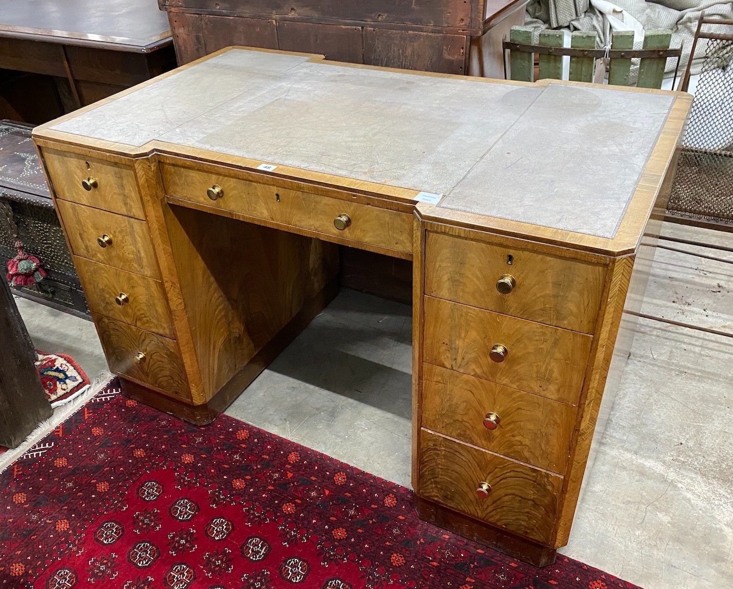 An Art Deco style walnut inverse breakfront kneehole desk, length 122cm, depth 72cm, height 76cm